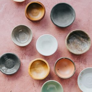Small glazed tasting bowls in blue, white and amber on a pink table