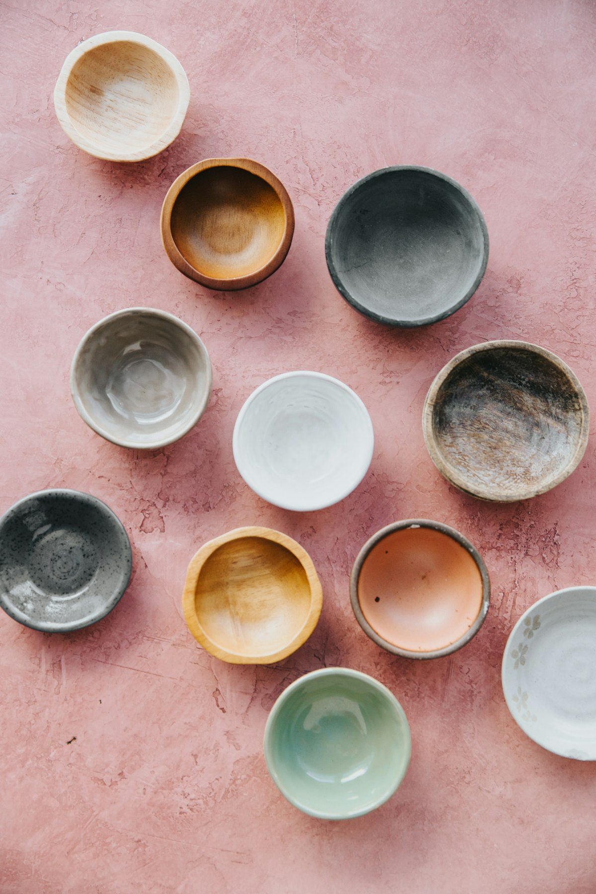 Small glazed tasting bowls in blue, white and amber on a pink table