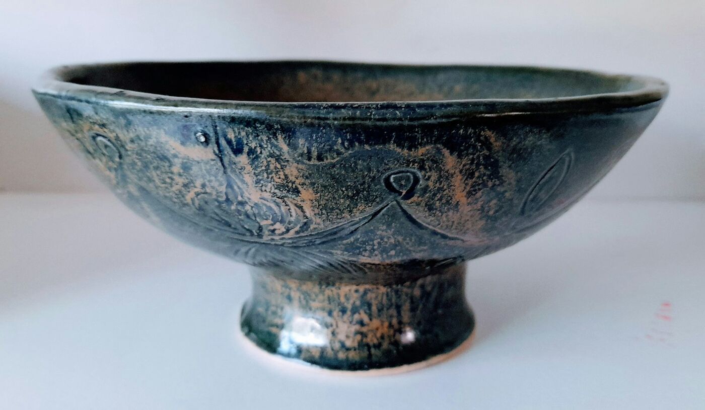 A deep blue glazed bowl on a small foot