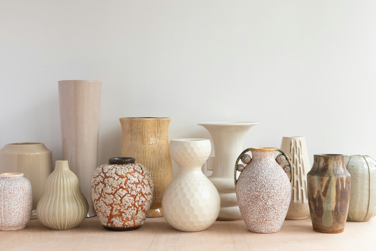 Finished stoneware vases in soft glazes lined up on a shelf