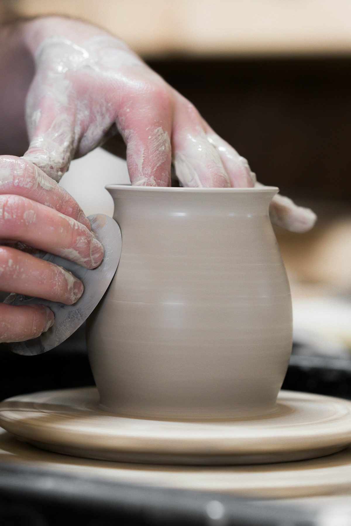 A potter lifting the walls of a pot on the wheel