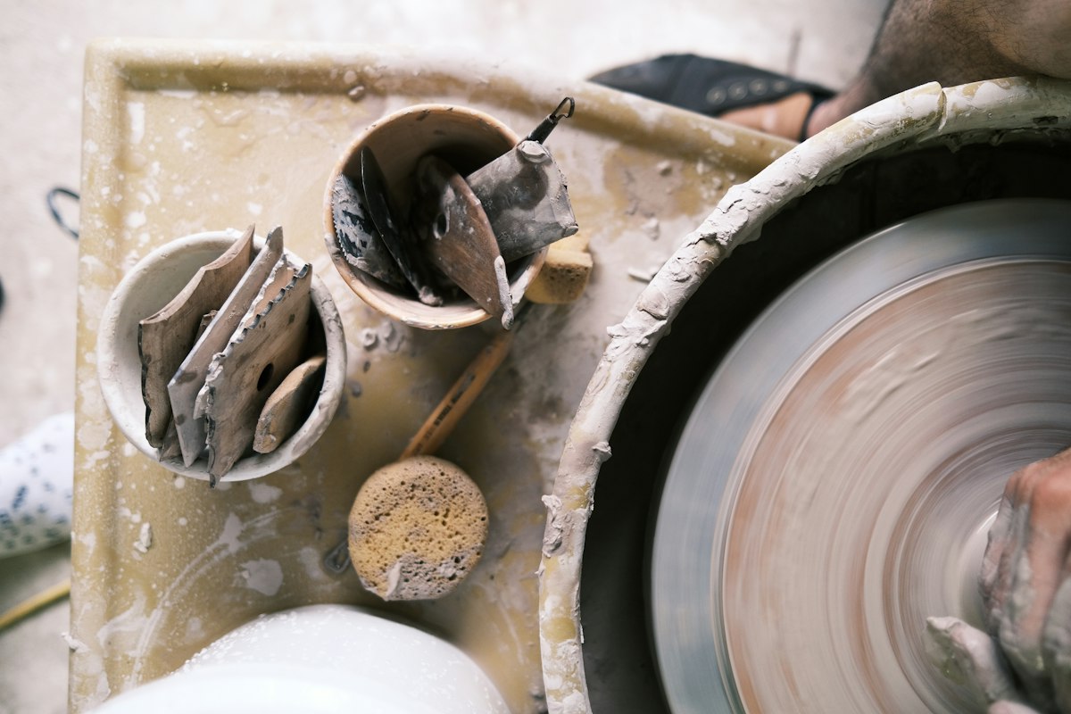 Clay tools in pots beside a turning potter's wheel