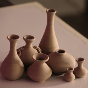 Terracotta bud vases of different heights on a pink table