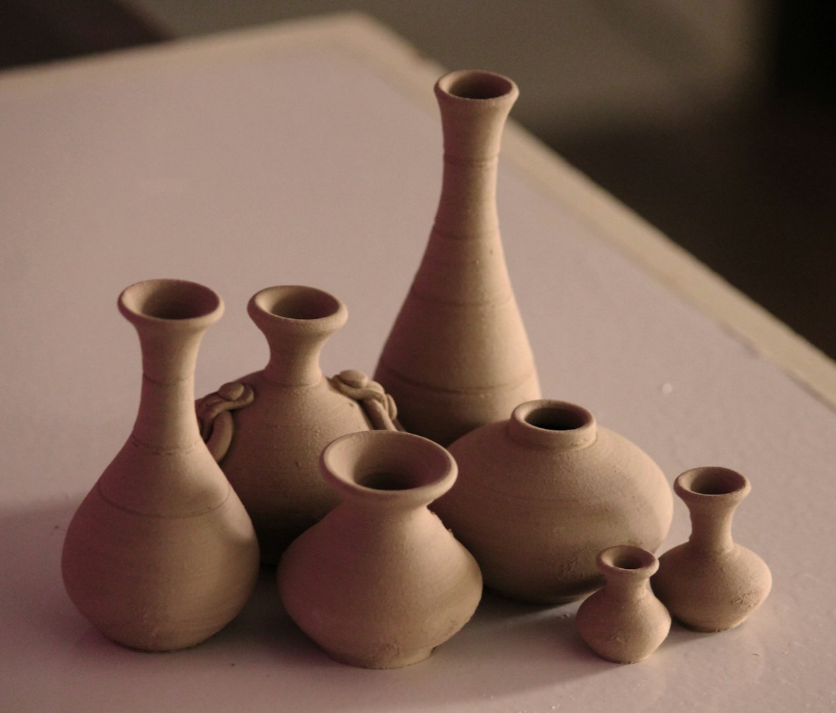 Terracotta bud vases of different heights on a pink table